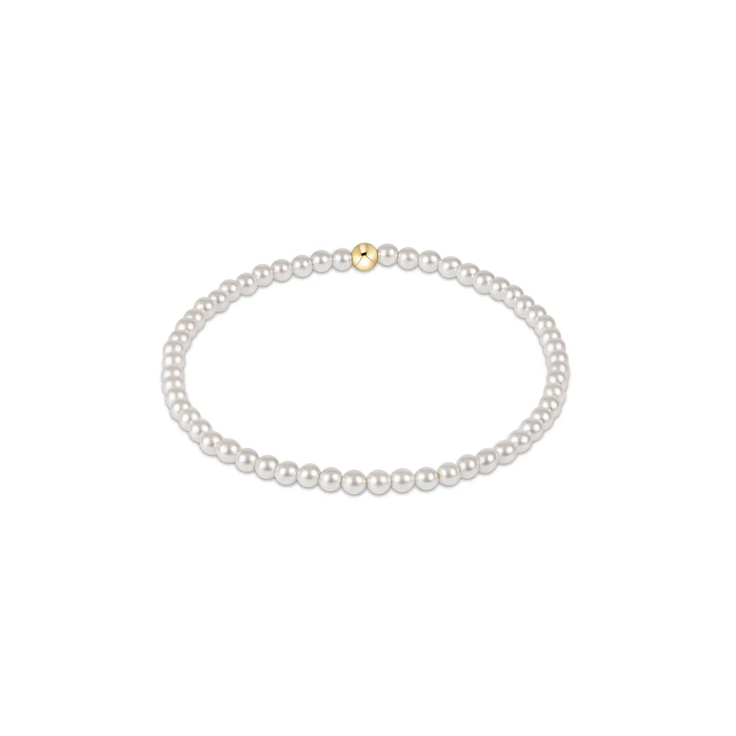 A pearl bead bracelet with a single gold bead at the top.