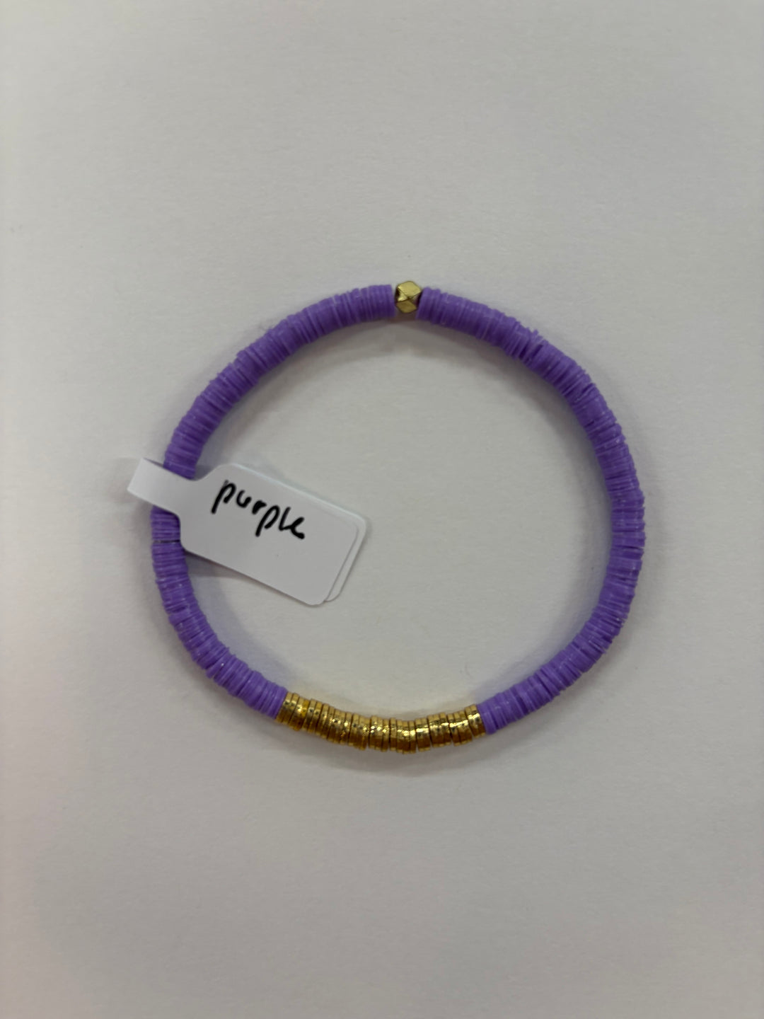 A purple flat bead bracelet with gold accents and a "purple" tag.