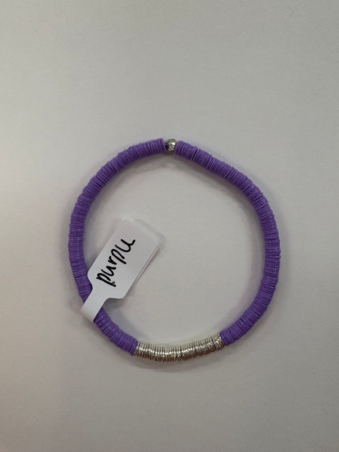A purple flat bead bracelet with silver-plated accents and a tag reading "purple."