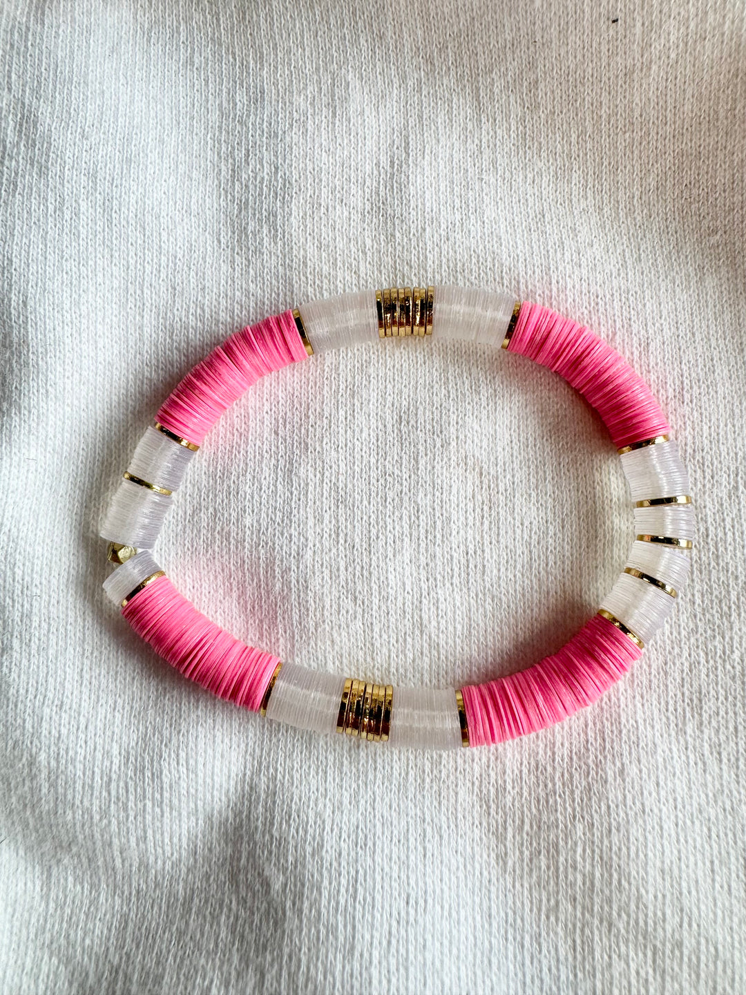 Large flat bead bracelet with pink and clear vinyl beads and gold accents.