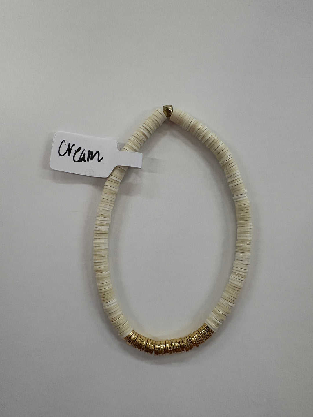 Cream flat bead bracelet with gold-plated accents.