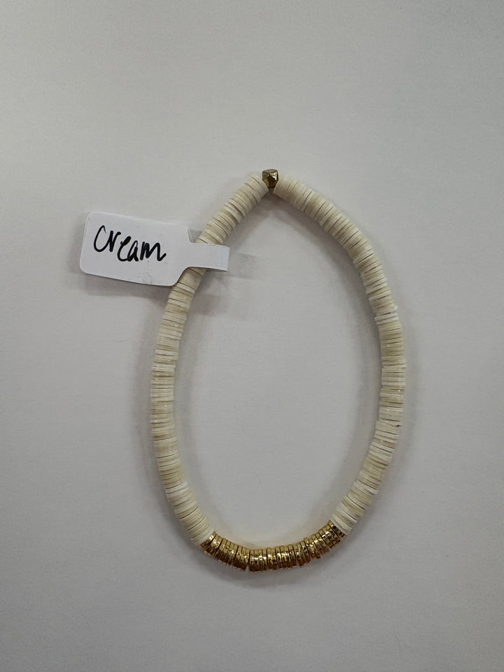 Cream flat bead bracelet with gold-plated accents.