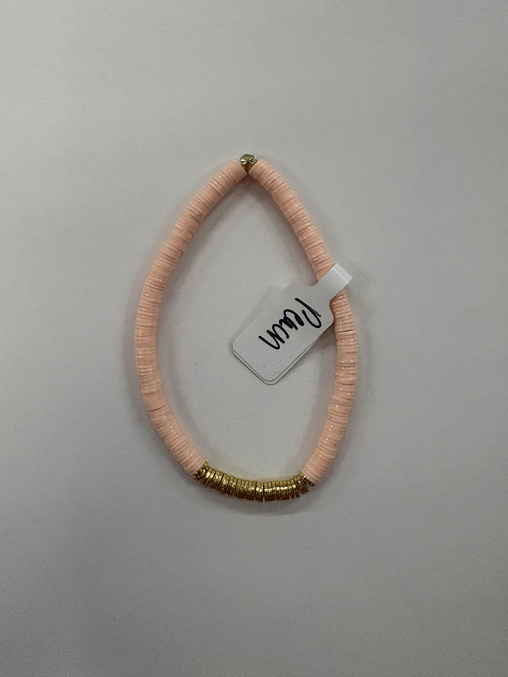 A light pink flat bead bracelet with a section of gold-colored beads and a white tag.