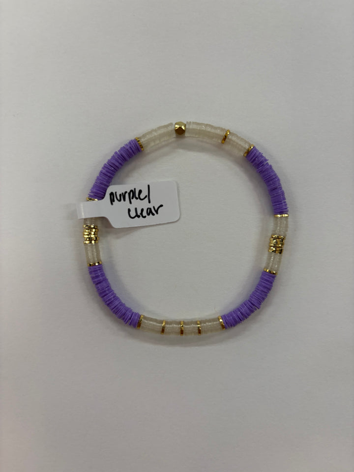 A purple and clear flat bead bracelet with gold accents and a tag reading "purple clear."