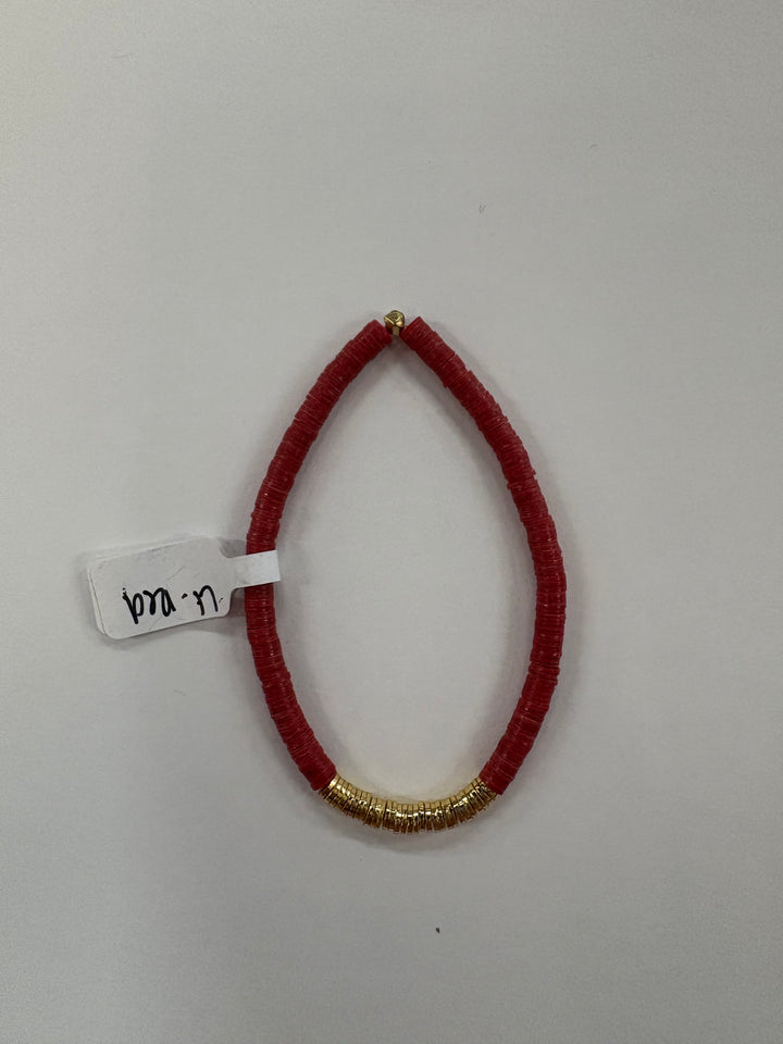 Small red flat bead bracelet with a section of gold-plated beads and a white tag.