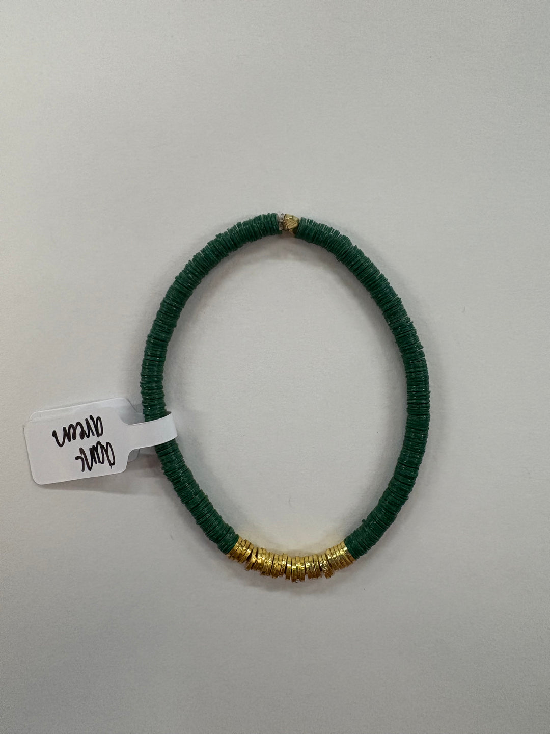 A dark green flat bead bracelet with gold-plated accents and a tag reading "dark green."