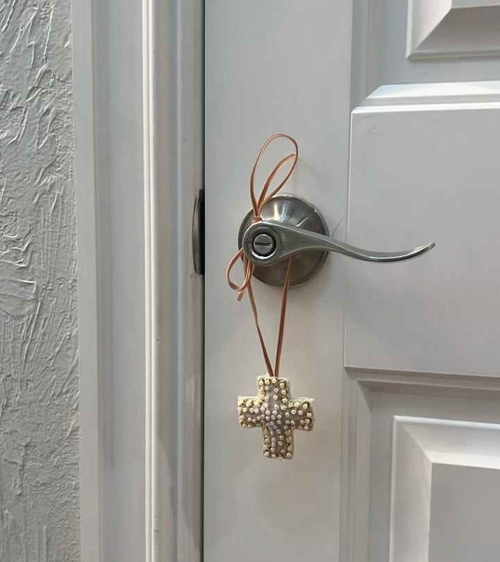 Mini Cross Hand Beaded Ornament hanging from a silver door handle.