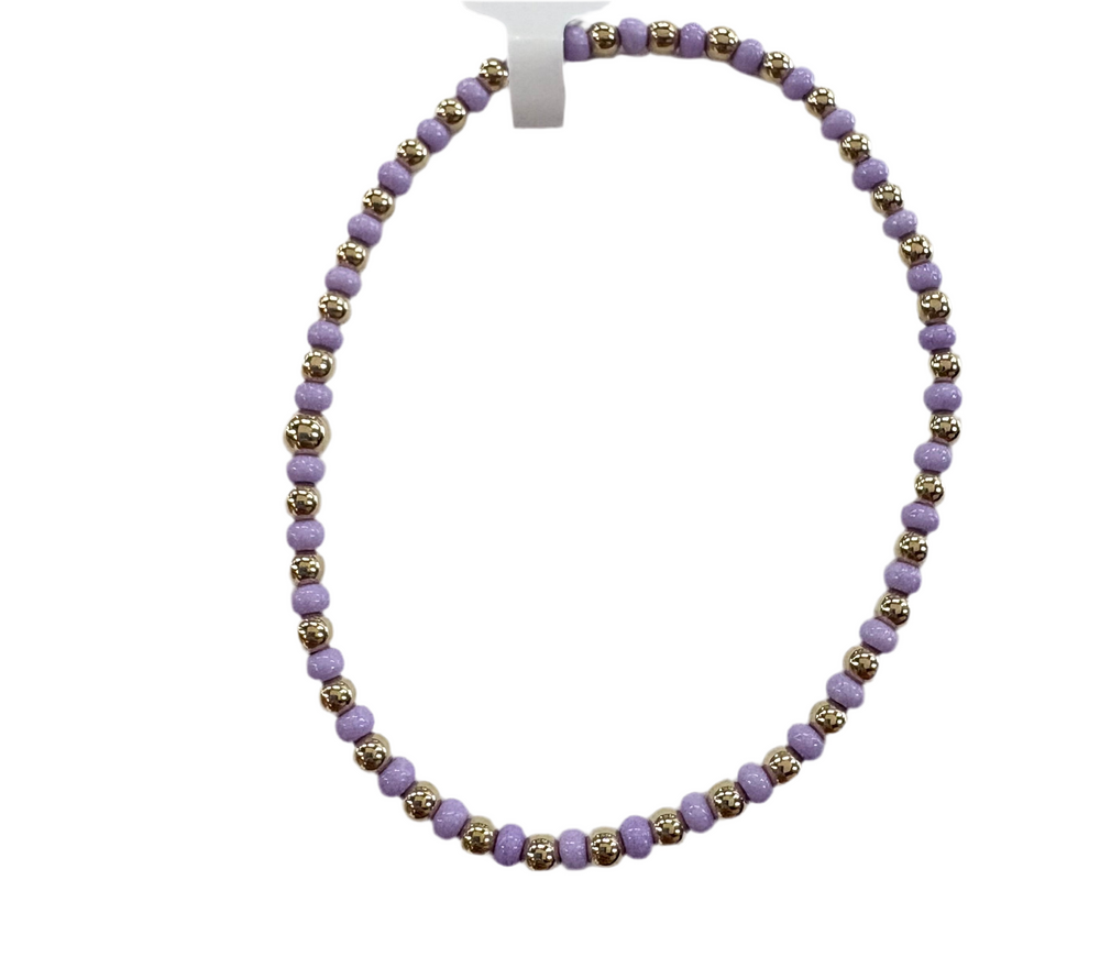 A bracelet made of alternating gold and lavender glass beads.