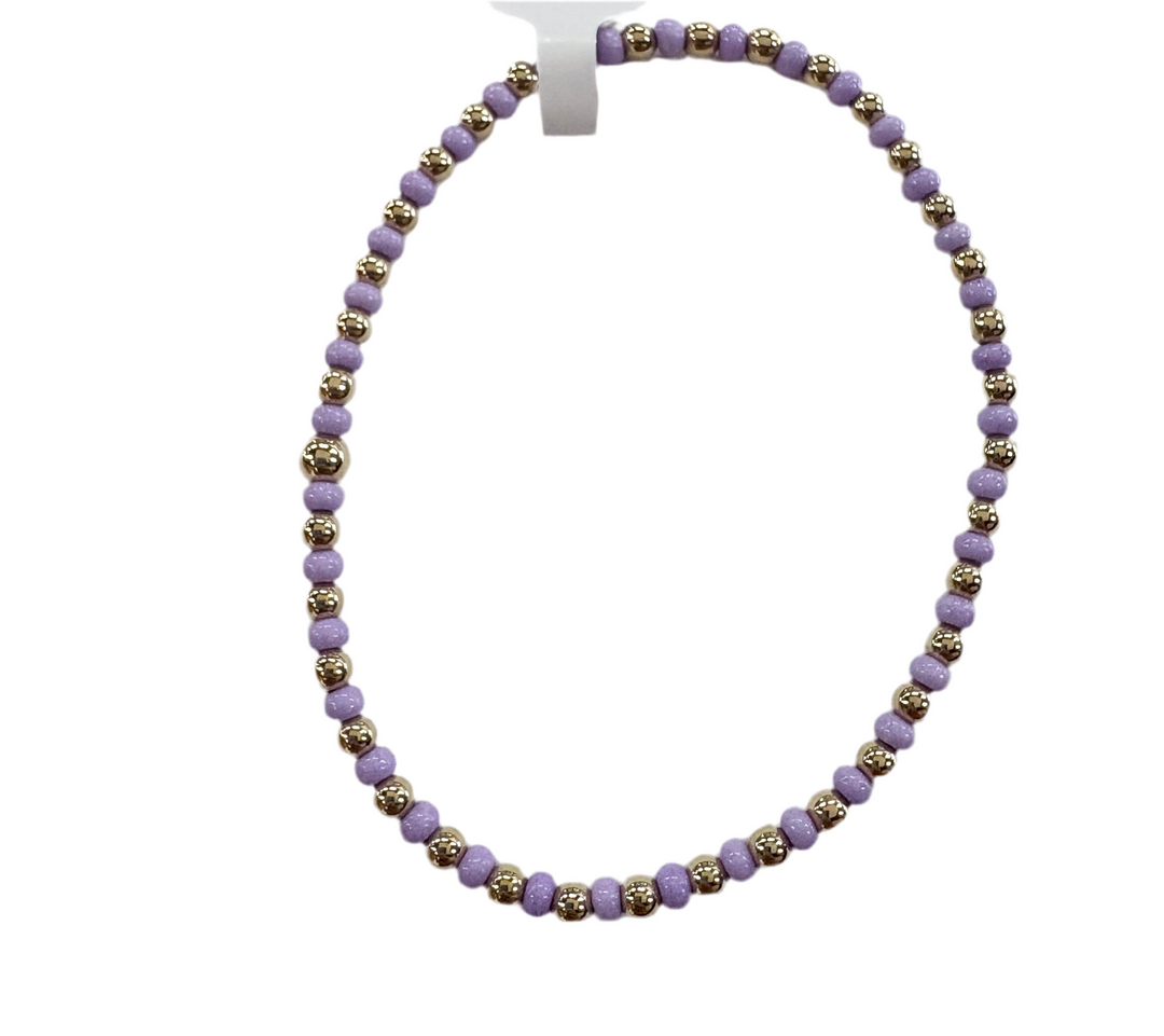 A bracelet made of alternating gold and lavender glass beads.