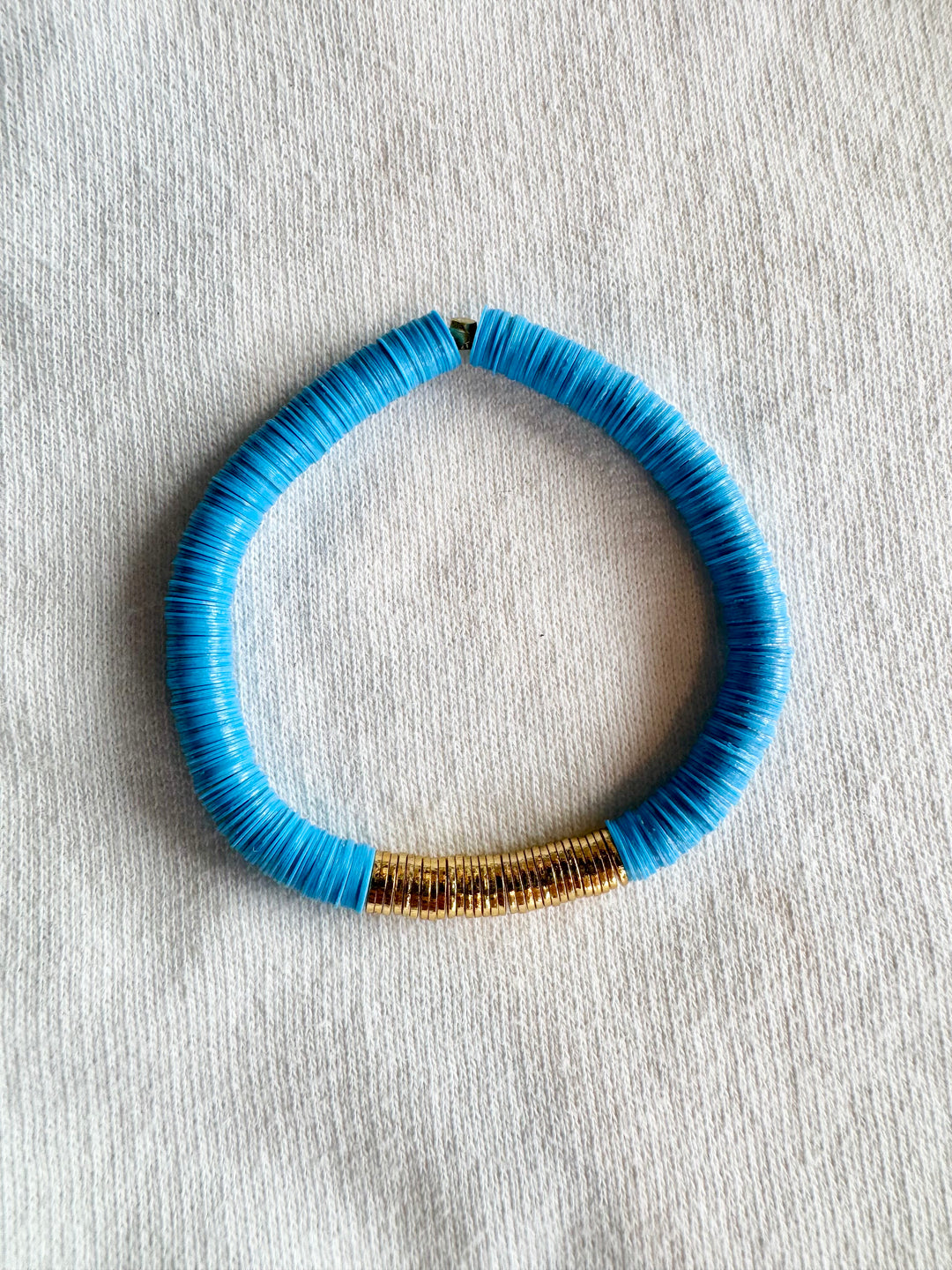A large, flat bead bracelet with blue vinyl beads and gold-plated accents.