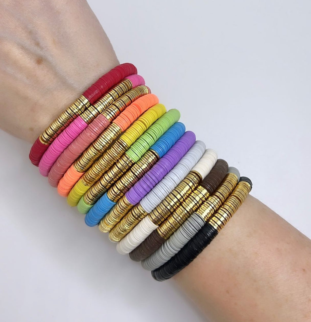 A person's arm displays a stack of colorful flat bead bracelets with gold accents.