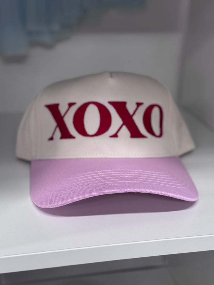 A cream and pink baseball cap with red XOXO embroidery.