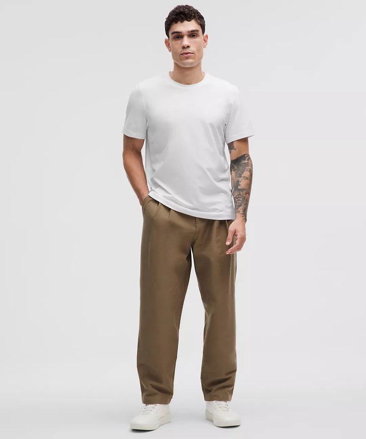 Man wearing a white short-sleeve t-shirt and brown pants.