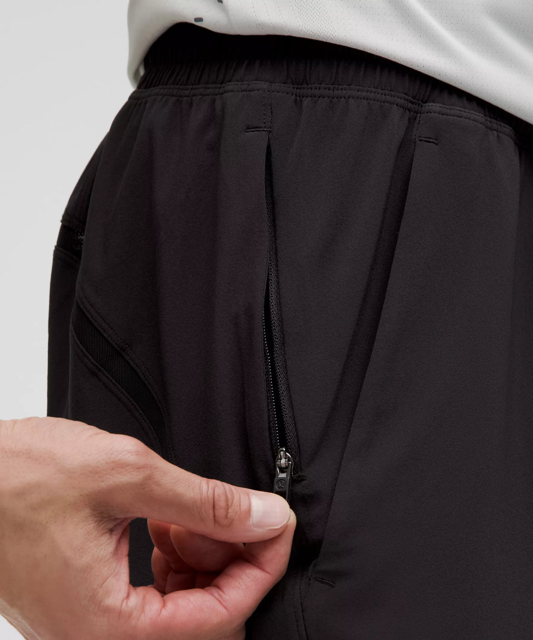 Black Pace Breaker Linerless Short 7" with a hand opening a zippered pocket.