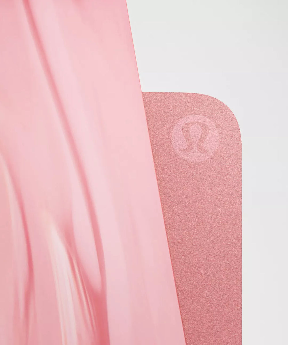 A pink yoga mat with a subtle logo.