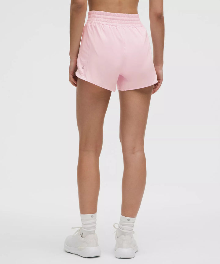 A person from behind wearing pink high-rise lined shorts, white socks, and white sneakers.