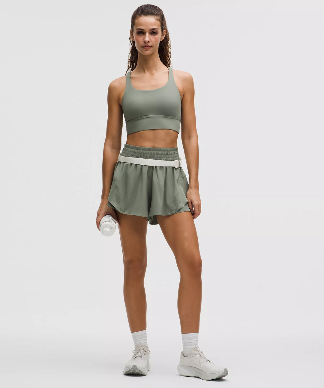 Women's green running shorts with a white waistband and a white water bottle.