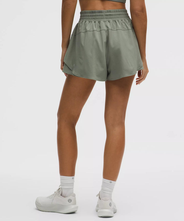 Women's green running shorts with a high-rise waistband and layered hem.