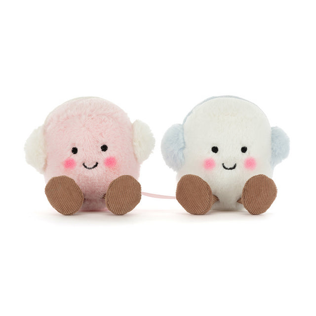 Two plush marshmallows, one pink and one white, wear earmuffs and smile.