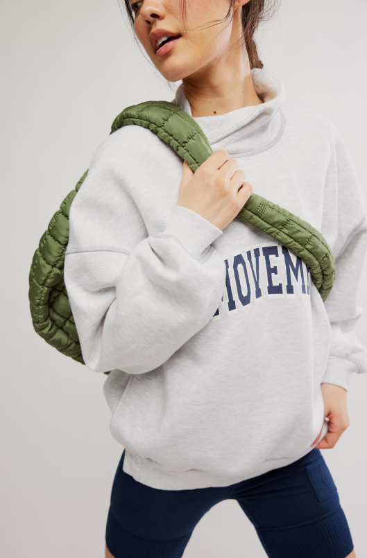 A woman wears a heather grey oversized sweatshirt with a funnel neck and navy biker shorts.