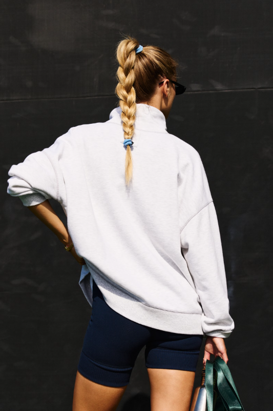 A woman from behind wears a heather grey oversized sweatshirt and navy biker shorts.