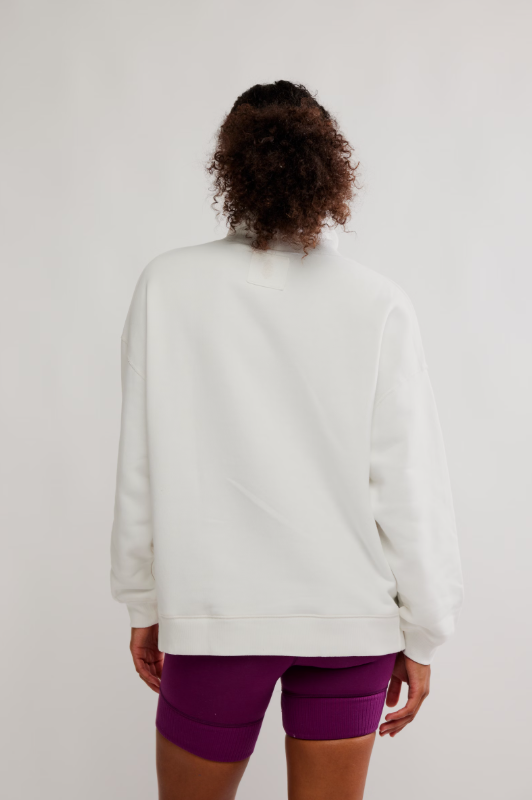 A person from behind wears an oversized white pullover and deep mulberry biker shorts.