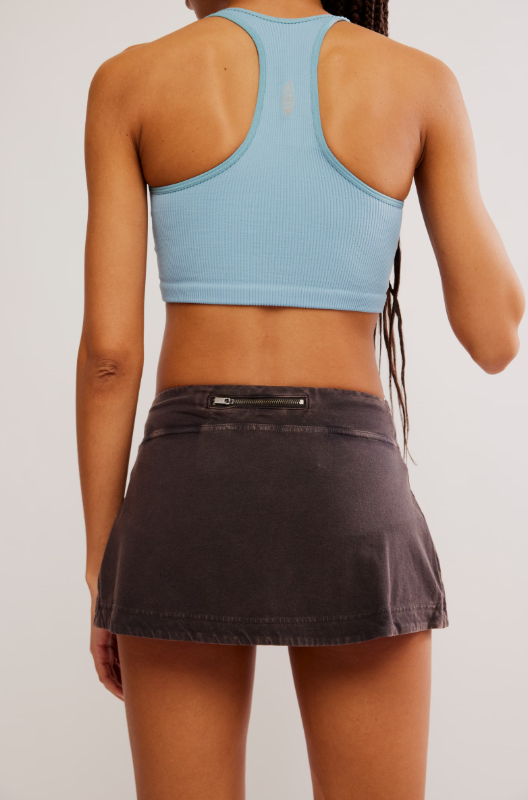Black mini skort with a zippered back pocket and a light blue ribbed sports bra.