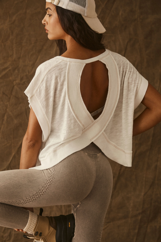 White tee with a wrapped cutout back and light brown leggings.