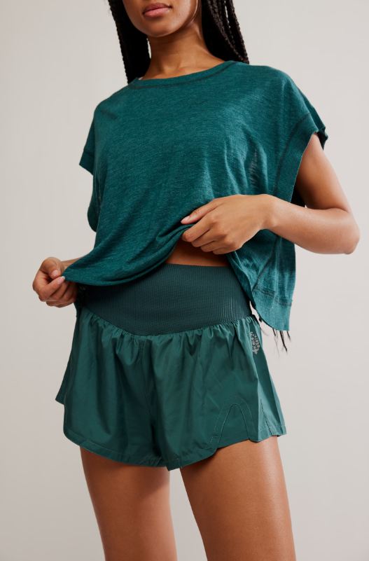 A woman wears a teal t-shirt and matching teal shorts with a textured waistband.