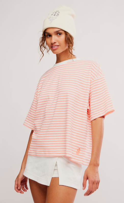 A woman wears a striped t-shirt and white shorts.