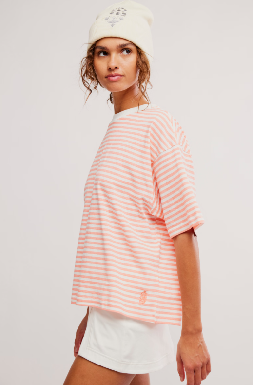 A woman wears a striped t-shirt and white shorts.