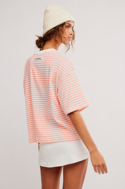 A woman wears a striped t-shirt and white skirt.