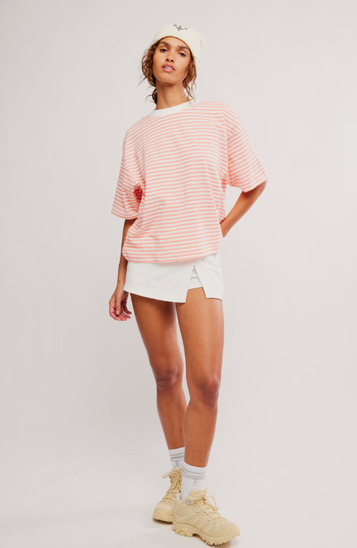 A woman wears a striped t-shirt and white skort.