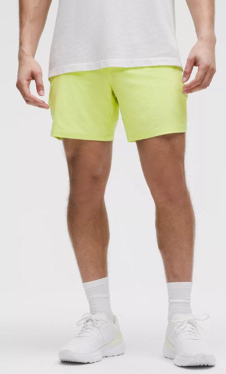 Men's lime green athletic shorts with white socks and shoes.