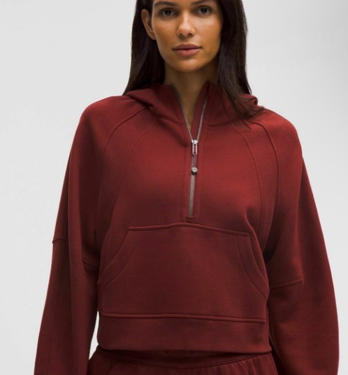 A woman wears a maroon oversized half-zip hoodie with a kangaroo pocket.