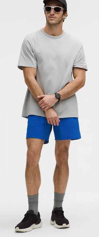 Men's blue linerless training shorts with a grey t-shirt and black sneakers.