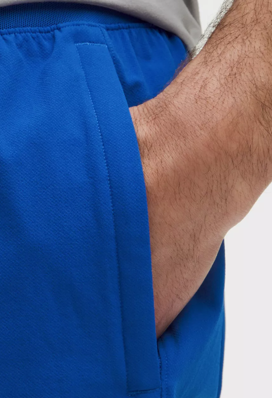 Blue athletic shorts with a hand in the pocket.