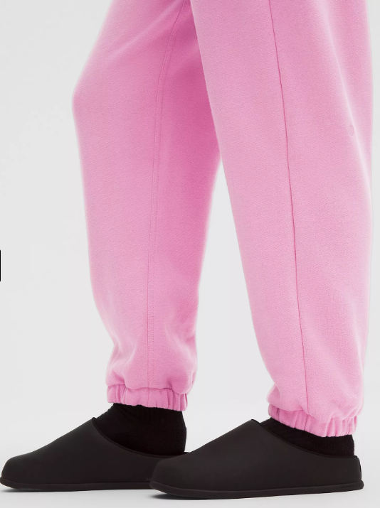 Pink oversized joggers with black slippers and socks.