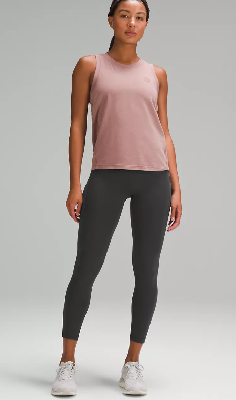 A woman models graphite grey Wunder Train high-rise leggings with pockets and a mauve tank top.