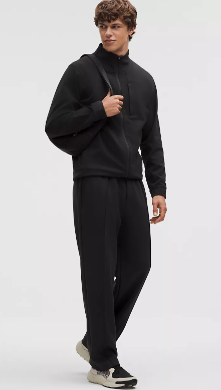 A man wears a black Sojourn jacket and black pants.