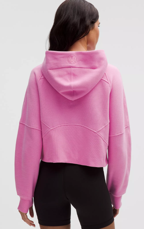 Back view of a pink cropped hoodie with a logo on the hood.