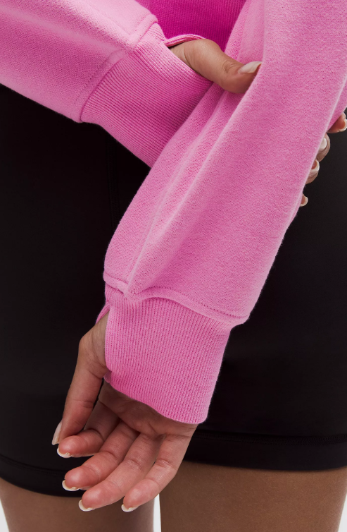 A pink oversized half-zip hoodie with thumbholes and a ribbed cuff.