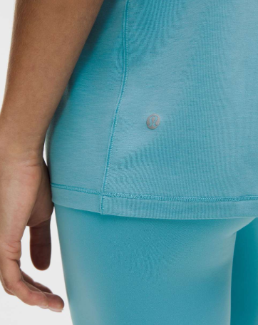 A close-up of a washed blue jersey training short sleeve shirt with a small logo.