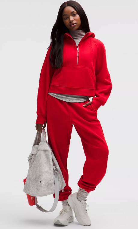A woman models a red oversized half-zip hoodie and matching joggers.