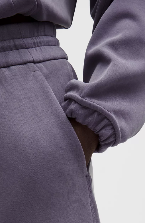 Close-up of purple high-rise shorts with a drawstring waist and cuffed hem.