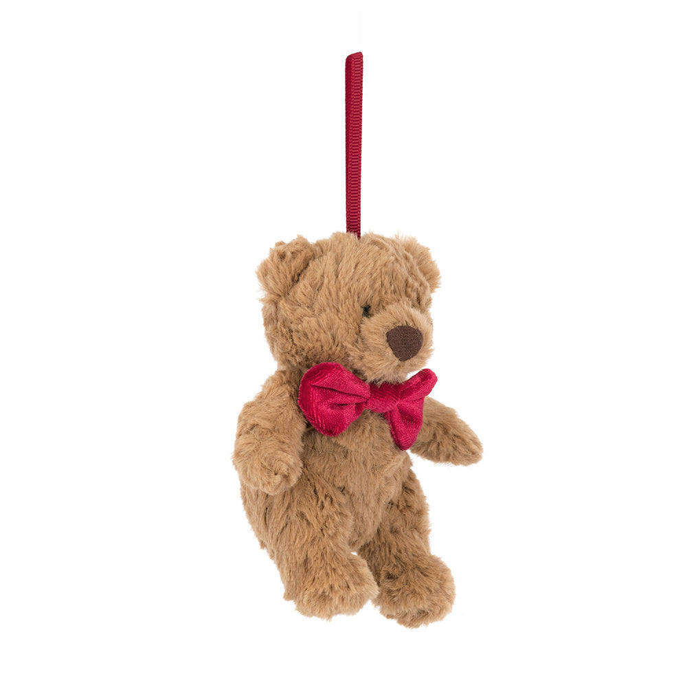 A small brown teddy bear ornament with a red bow tie hangs from a red ribbon.