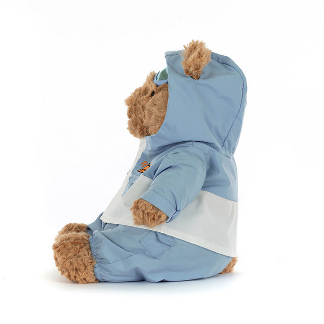 A brown teddy bear wearing a light blue and white snowsuit with a hood and goggles.