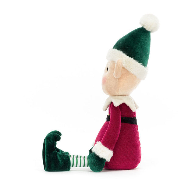 Eldo Elf plush toy in a red suit and green hat, sitting and looking left.