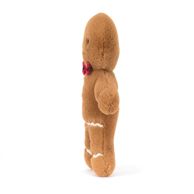 A plush gingerbread man with a red tartan bow stands facing right.