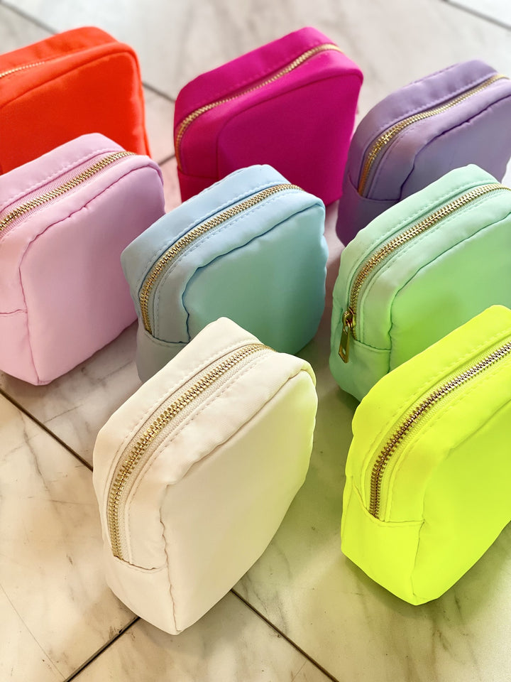 A collection of small nylon pouches in various bright and pastel colors with gold zippers.